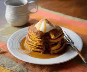 Fluffy buttermilk pumpkin pancakes topped with syrup and cinnamon, served on a plate for a cozy breakfast