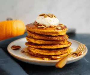 Delicious homemade pumpkin protein pancakes topped with syrup and fresh berries, perfect for a healthy breakfast