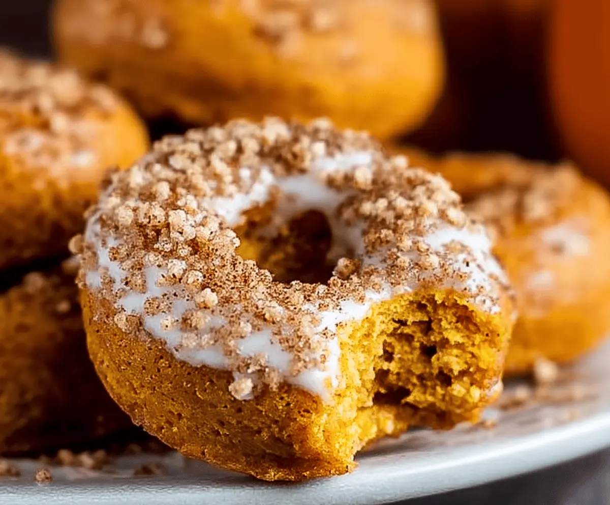 Delicious homemade pumpkin baked donuts topped with cinnamon glaze and sprinkles, perfect for fall treats.