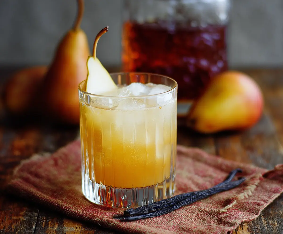 Refreshing Vanilla Pear Bourbon Cocktail in a elegant glass garnished with pear slices and vanilla bean.