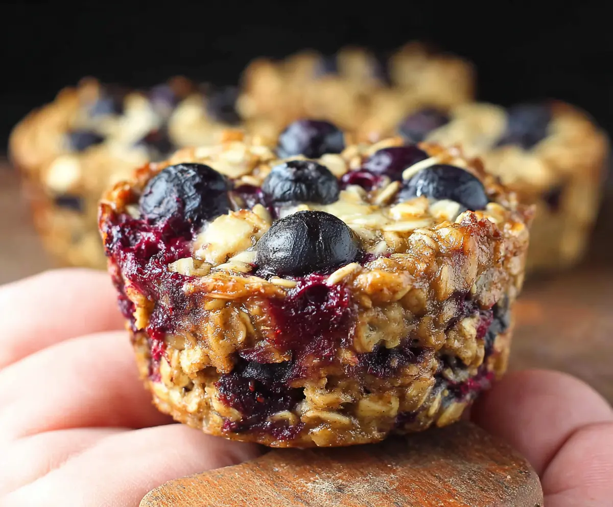 Healthy Blueberry Banana Baked Oatmeal Cups in a muffin tin, topped with fresh blueberries and sliced bananas.