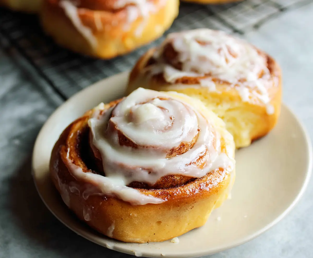 Freshly baked cinnamon rolls topped with creamy cream cheese frosting, perfect for breakfast or a sweet snack.