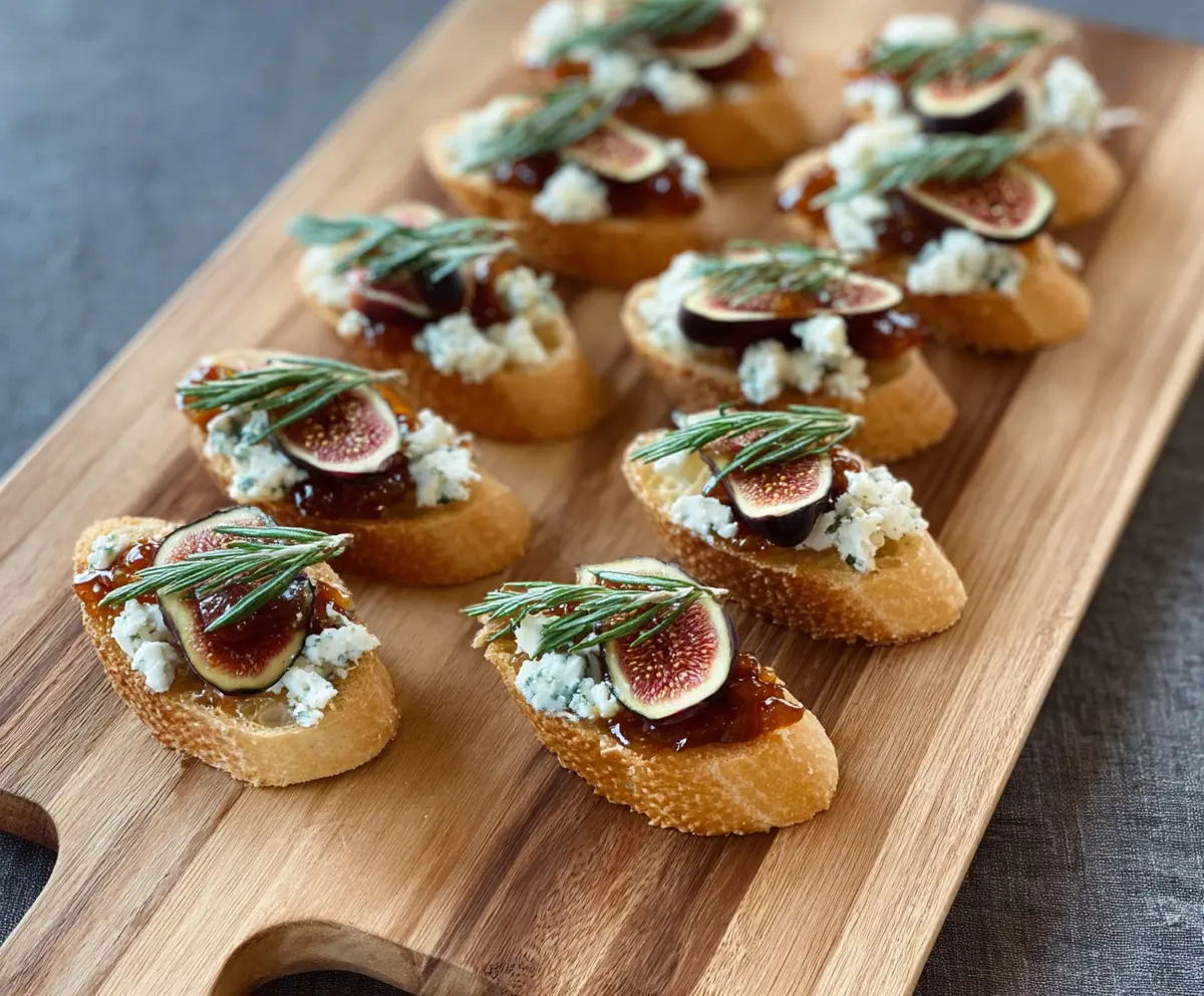 Delicious fig and blue cheese crostini served on a rustic wooden platter, perfect for appetizers.