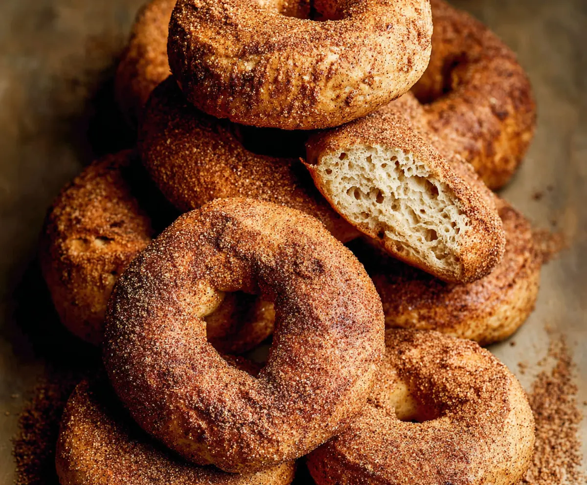Freshly baked cinnamon bagels on a wooden board, showcasing a golden-brown crust and sprinkled with cinnamon sugar.