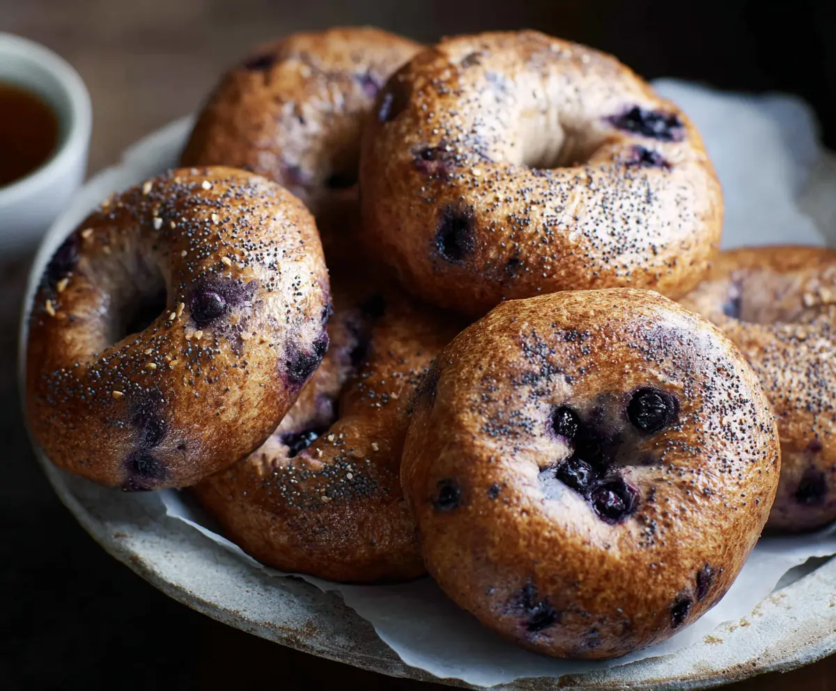 Freshly baked sourdough blueberry bagels on a wooden board, showcasing a golden crust and vibrant blueberries inside.