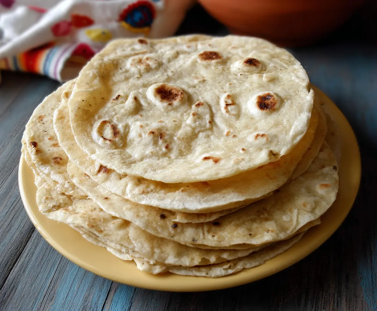 Delicious homemade sourdough butter tortillas on a rustic wooden surface.