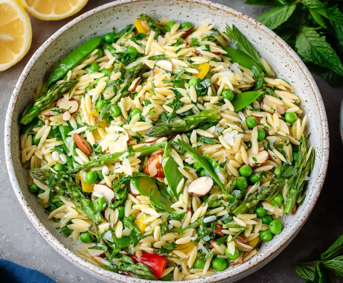 Colorful spring orzo pasta salad with fresh vegetables and herbs, perfect for a light meal or side dish.