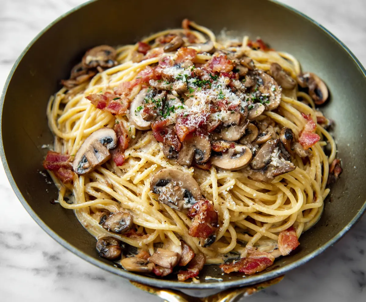 Delicious bacon mushroom pasta served on a plate, featuring crispy bacon and sautéed mushrooms.