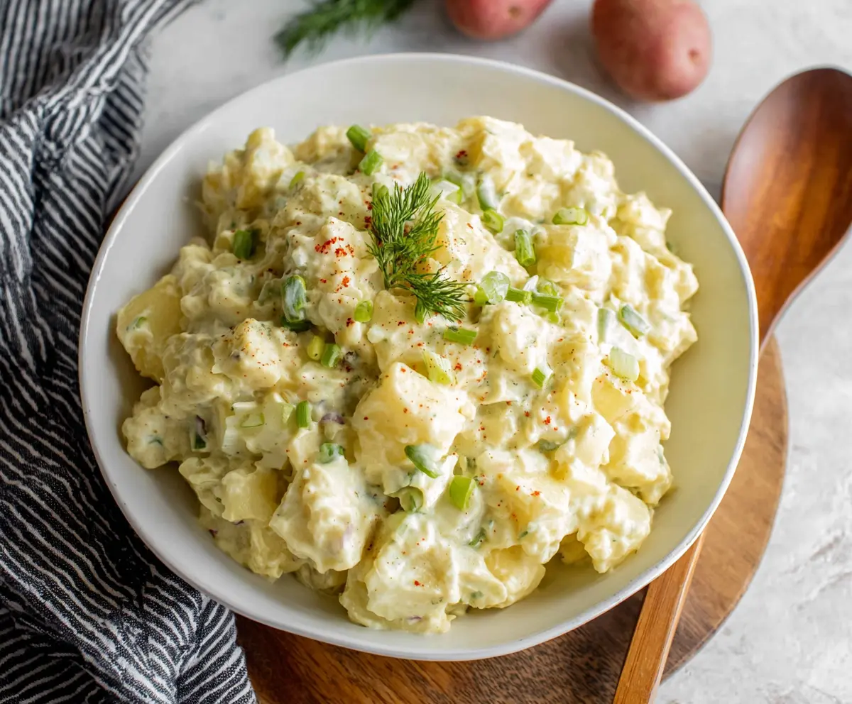 Delicious creamy potato salad with fresh herbs and a creamy dressing on a serving dish.