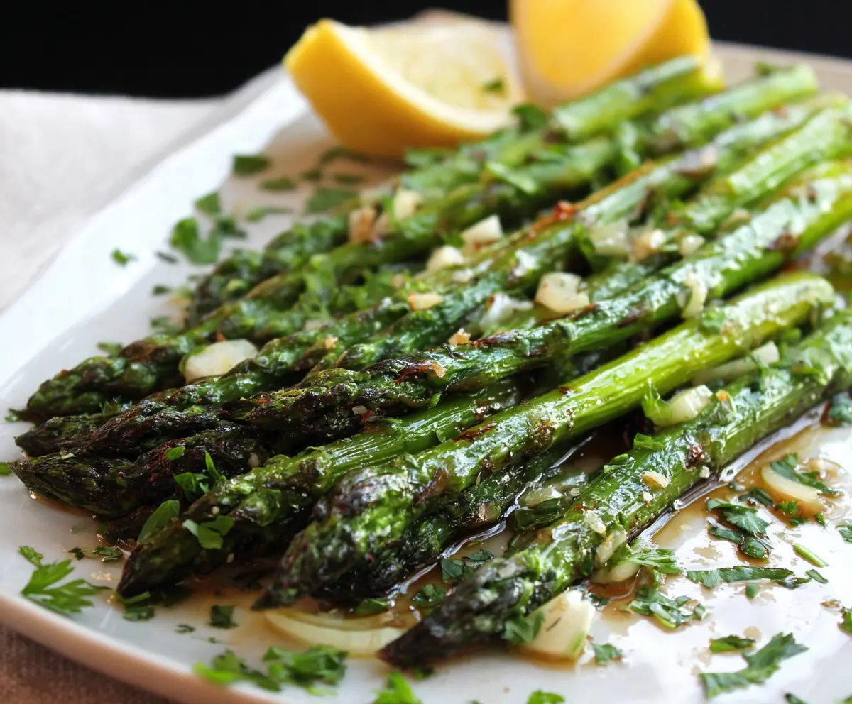 Delicious garlic herb roasted asparagus on a white plate, garnished with fresh herbs.