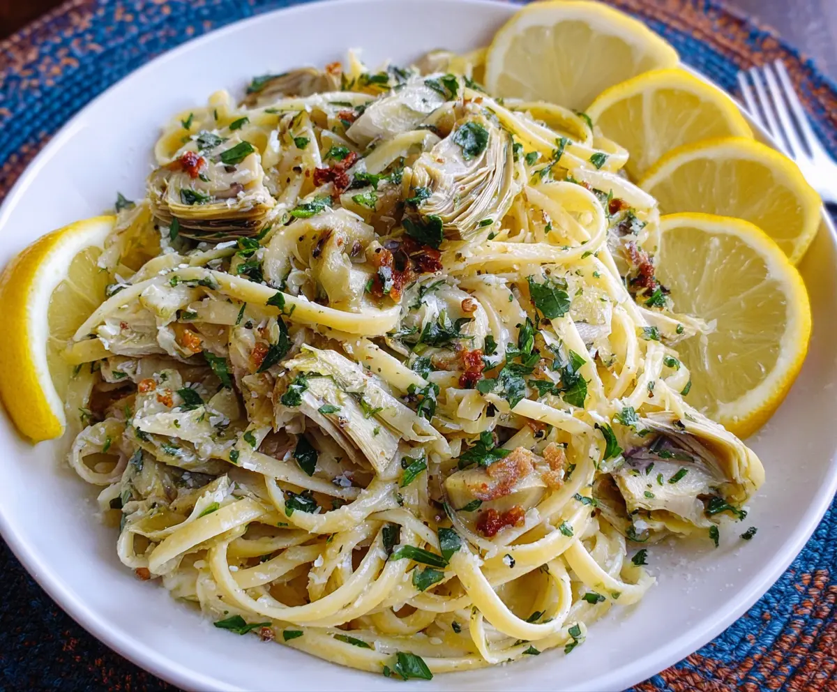 Delicious Lemon Artichoke Pasta garnished with fresh herbs on a white plate
